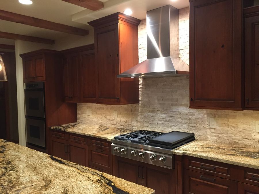 Dark wood kitchen with pro range and stacked-stone backsplash